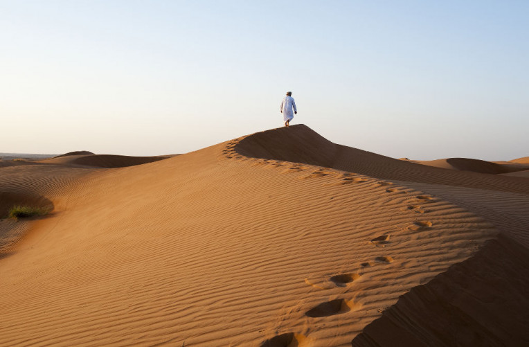012_Omani man walking on dunes © Ministry of Heritage & Tourism Sultanate of Oman